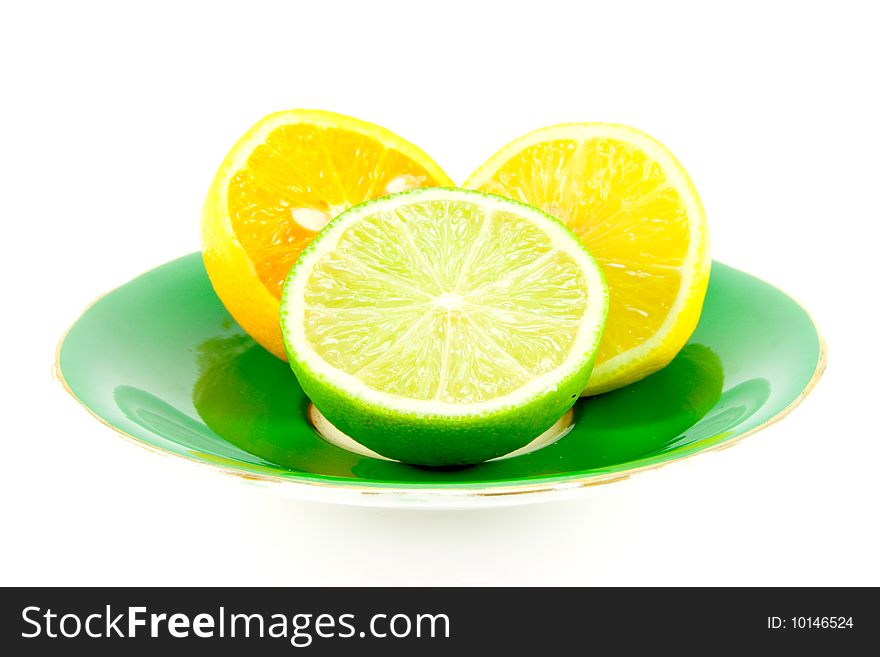 Lemon, lime and orange halves on a fancy green plate on a white background. Lemon, lime and orange halves on a fancy green plate on a white background