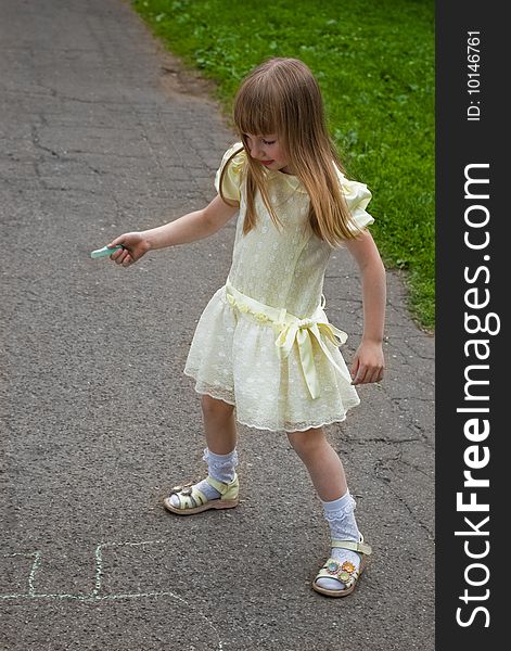 Smiling girl drawing with a crayoun on asphalt. Smiling girl drawing with a crayoun on asphalt