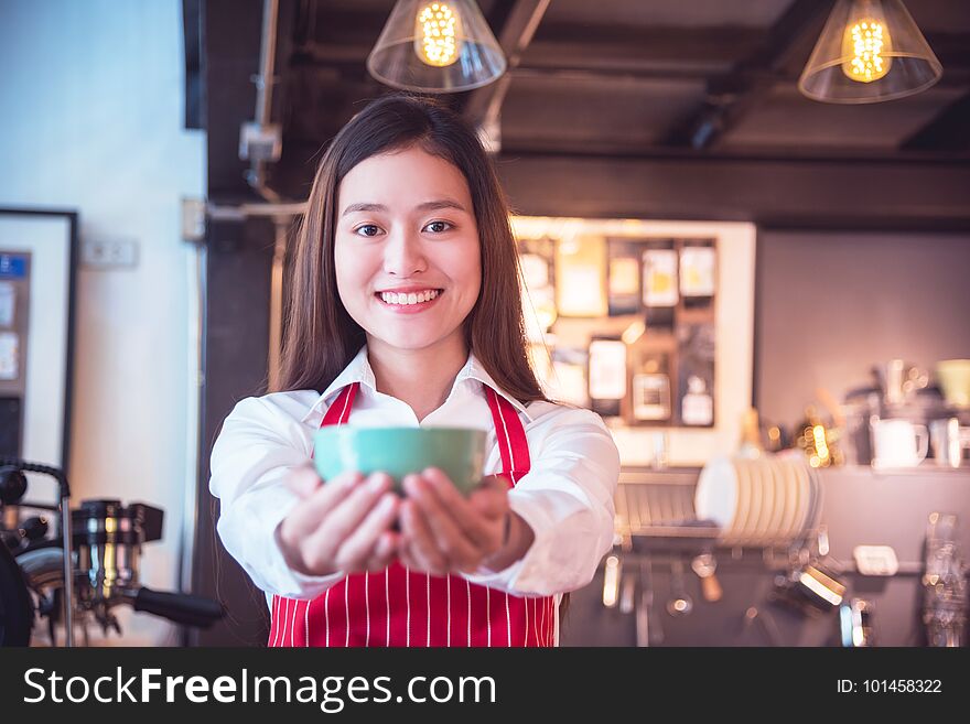 Barista wearing red color apron holding coffee cup