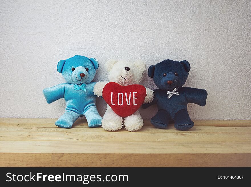 Lovely teddy bear and red heart shape sitting on wood table