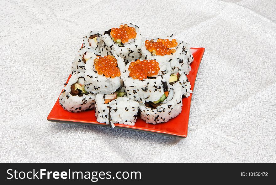 Homemade inside-out maki sushi with red caviar on red square plate. Homemade inside-out maki sushi with red caviar on red square plate