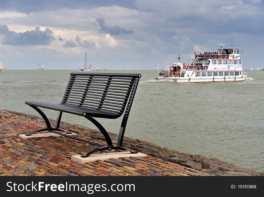 A bench and the boat from volenam to marken in the background, The Netherlands. A bench and the boat from volenam to marken in the background, The Netherlands