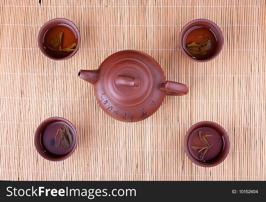 A teapot and four cups of bamboo in the background. A teapot and four cups of bamboo in the background.