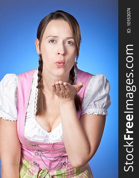 A woman dressed in a traditional Bavrian Dirndl blowing a kiss. A woman dressed in a traditional Bavrian Dirndl blowing a kiss.