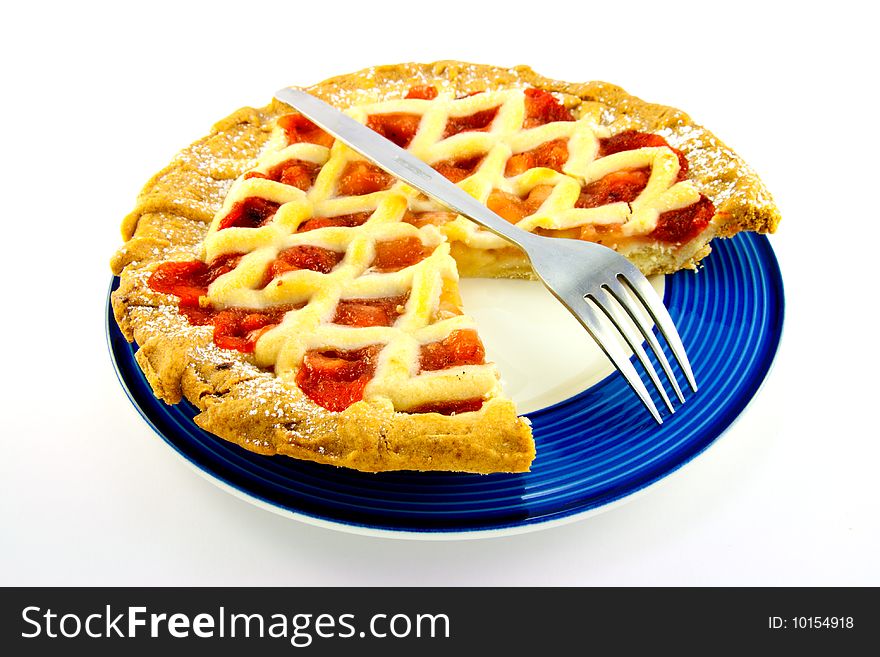 Whole apple and strawberry pie with a small fork on a blue plate with a slice missing on a white background. Whole apple and strawberry pie with a small fork on a blue plate with a slice missing on a white background