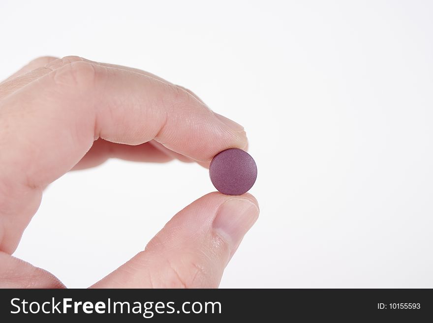 Two fingers holding a single purple round prescription pill. Two fingers holding a single purple round prescription pill