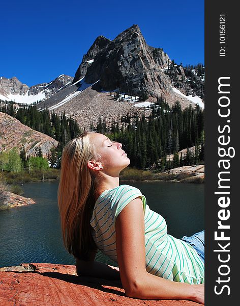 A beautiful woman enjoying the sun up at a mountain lake. A beautiful woman enjoying the sun up at a mountain lake.