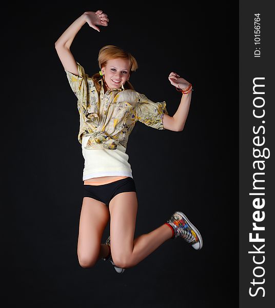 Beautiful young dancer jumping on a black background
