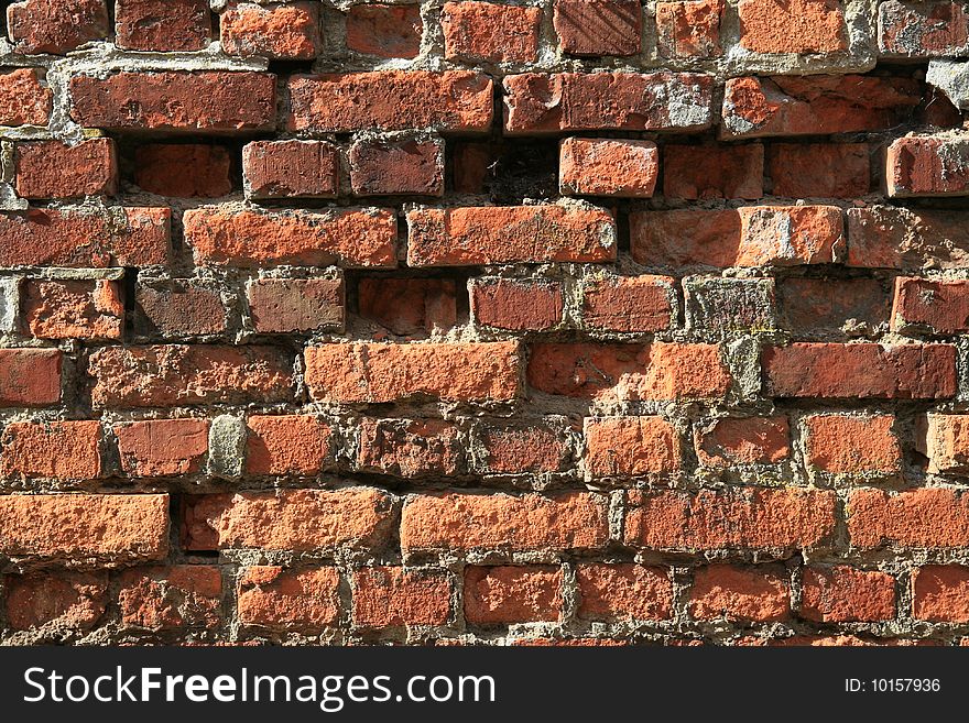 An old brick wall with some bricks missing or out of place