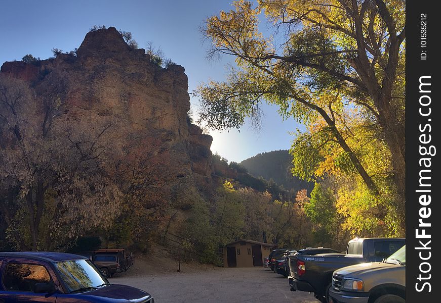 A parking lot with cars next to a stone cliff.