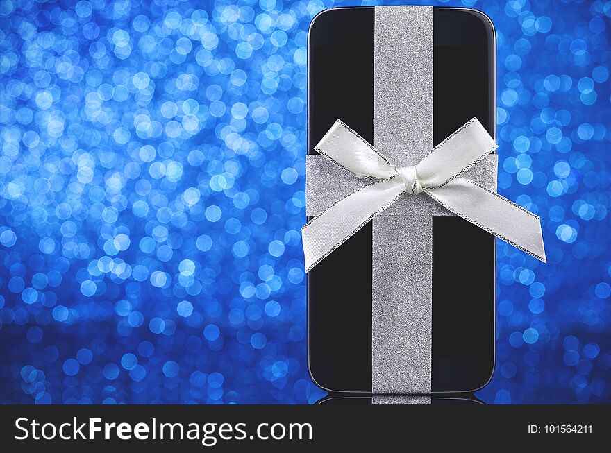 Smartphone gift for Christmas on blue defocused background