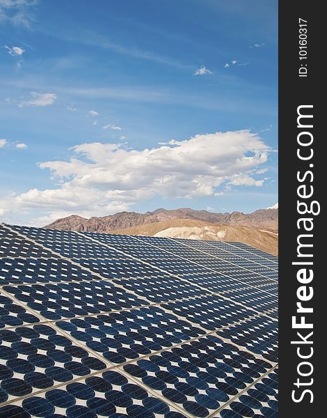 Solar panel with blue sky, clouds, and mountains in the background