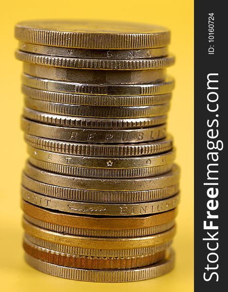 Stacked foreign coins on yellow background