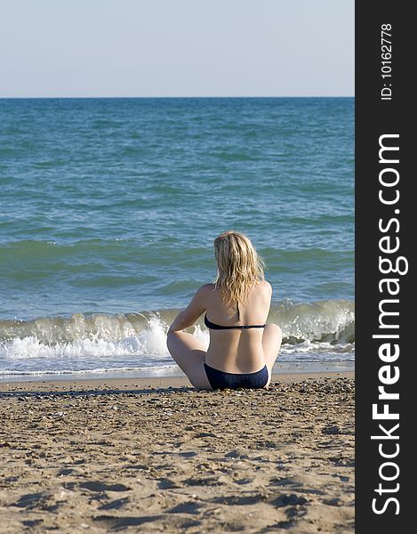 Girl sits on the beach of sea