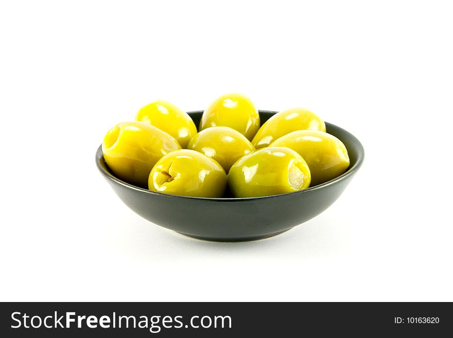 Green olives in a small round black bowl on a white background. Green olives in a small round black bowl on a white background