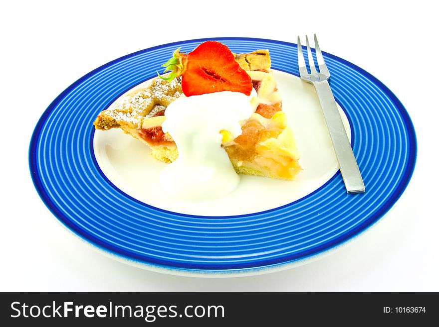 Slice of apple and strawberry pie with strawberries, cream and a fork on a blue plate with a white background. Slice of apple and strawberry pie with strawberries, cream and a fork on a blue plate with a white background