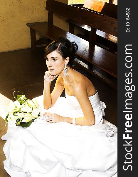 Beautiful brunette bride sitting on a step in the chapel. Beautiful brunette bride sitting on a step in the chapel