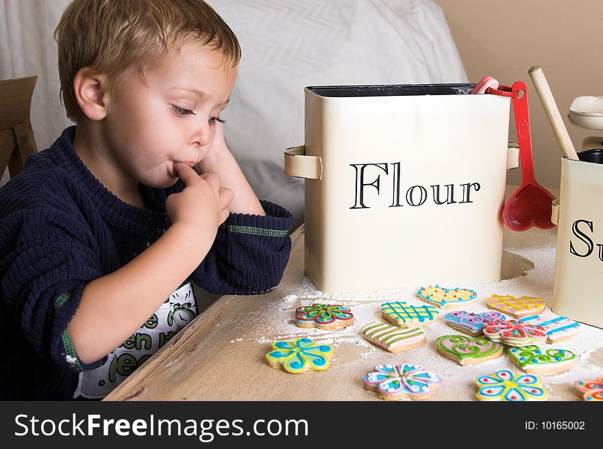 Young boy waiting at the kitchen table to taste newly decorated cookies. Young boy waiting at the kitchen table to taste newly decorated cookies