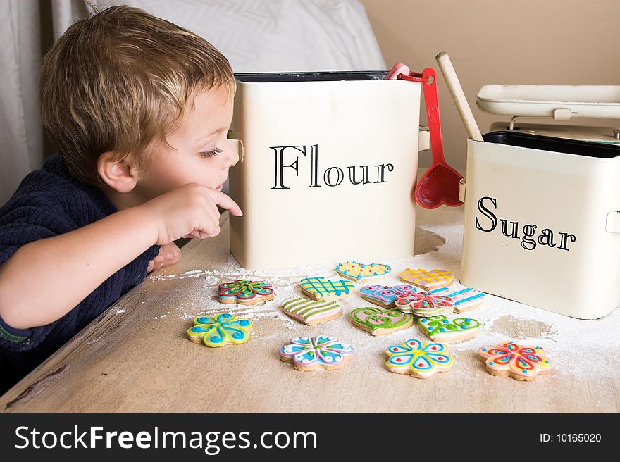 Young boy waiting at the kitchen table to taste newly decorated cookies. Young boy waiting at the kitchen table to taste newly decorated cookies