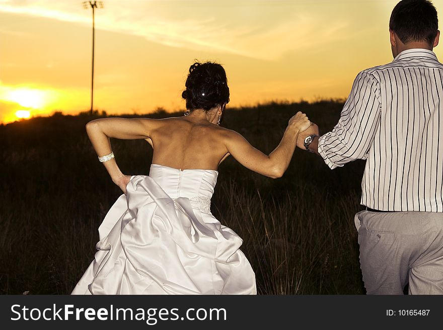 Bridal couple in the field as the sun sets