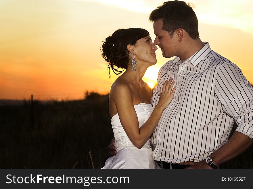 Bridal couple in the field as the sun sets