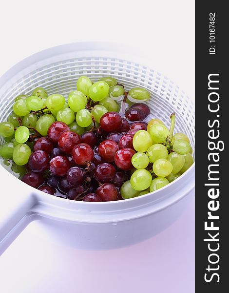 Grapes in strainer on white background