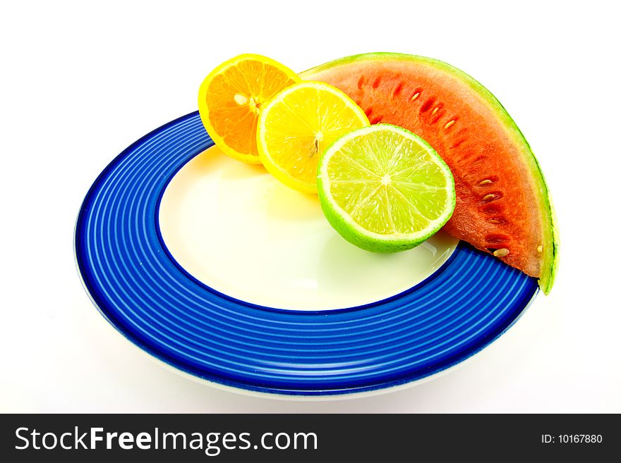 Slice of red juicy watermelon with lemon, lime and orange halves on a blue plate with a white background. Slice of red juicy watermelon with lemon, lime and orange halves on a blue plate with a white background