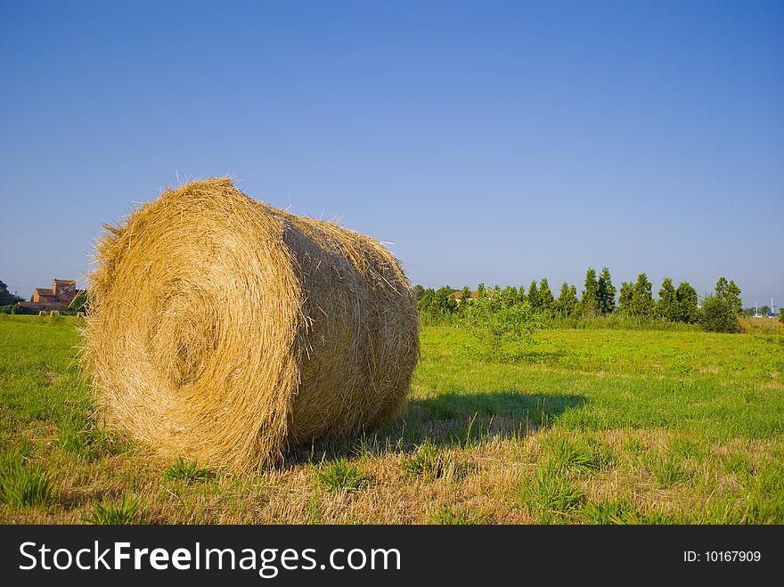 Large roll of straw, on a green lawn in the open countryside. Large roll of straw, on a green lawn in the open countryside