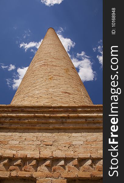 An old brick chimney against the blue sky