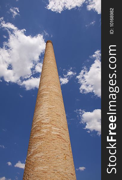An old brick chimney against the blue sky