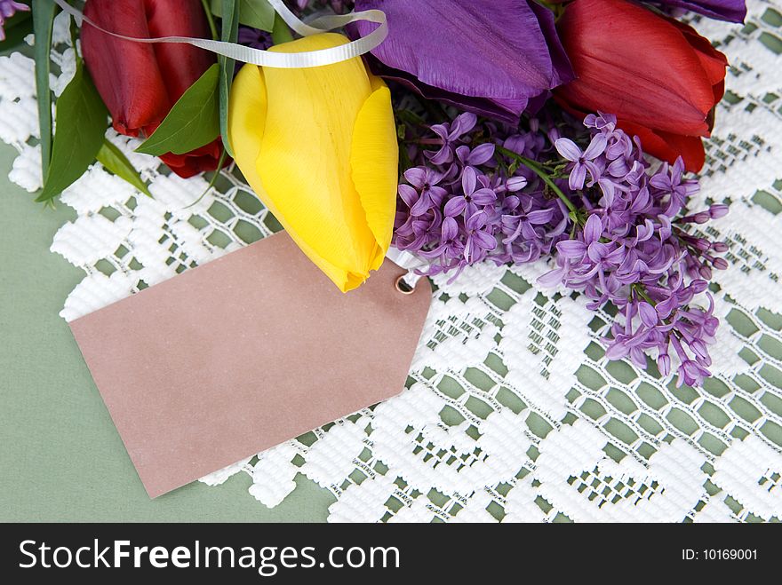 A bouquet of spring tulips with blank gift tag on lace background. A bouquet of spring tulips with blank gift tag on lace background