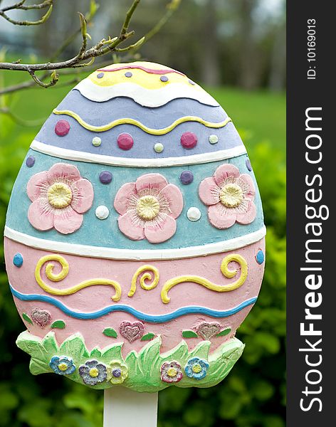 A wooden pastel colored Easter egg garden sign, vertical with copy space. A wooden pastel colored Easter egg garden sign, vertical with copy space