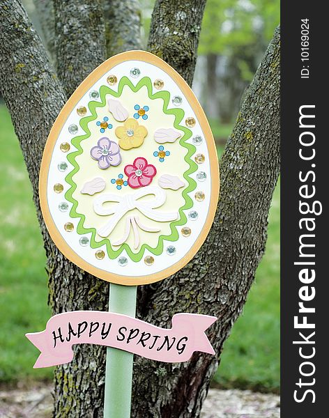 A colorful wooden Easter egg Happy Spring garden sign, vertical with copy space