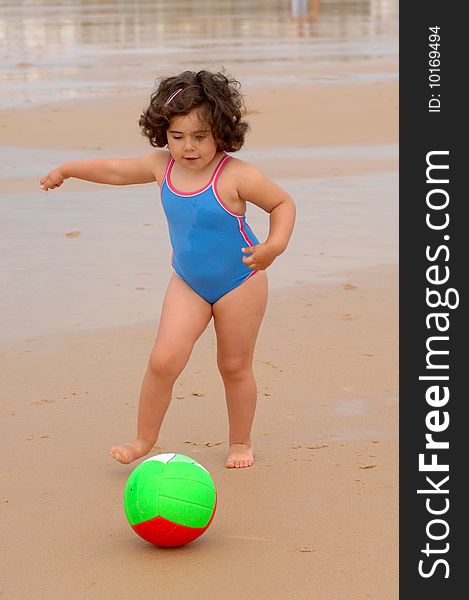 Cute little girl on the beach playing with a ball