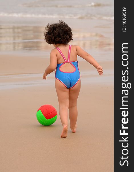 Cute little girl on the beach playing with a ball