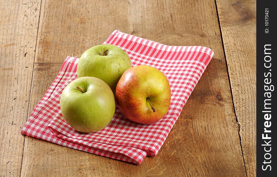 Three fresh apples on a rustic table