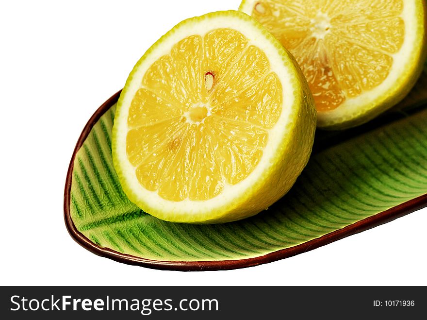 Cut lemons on green dish isolated on white background