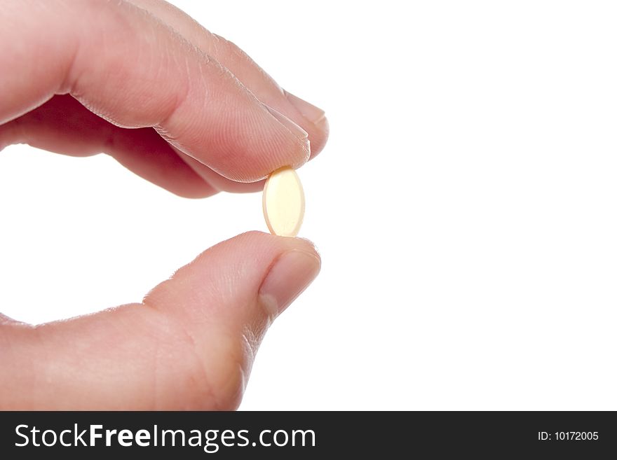 Two fingers holding a small cream prescription pill. Two fingers holding a small cream prescription pill