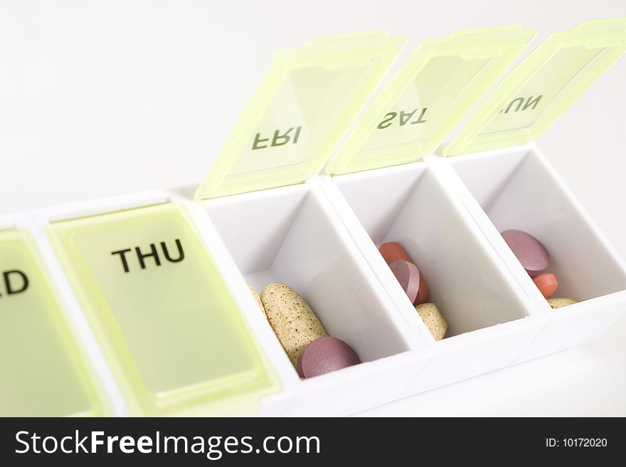 Weekly pill organizer with an assortment of pills and vitamins inside