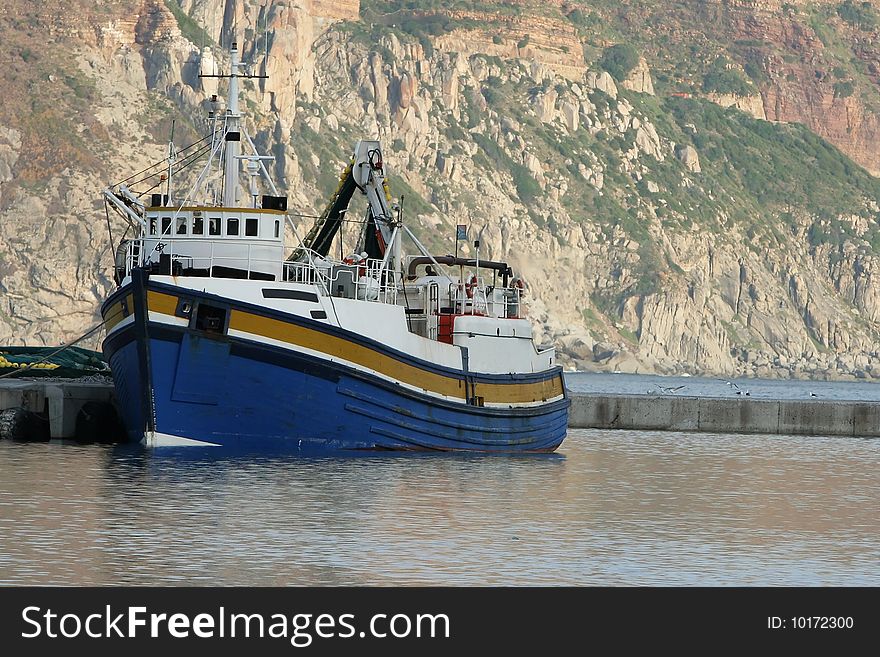 Boat docked in harbor with cliff in background. Boat docked in harbor with cliff in background