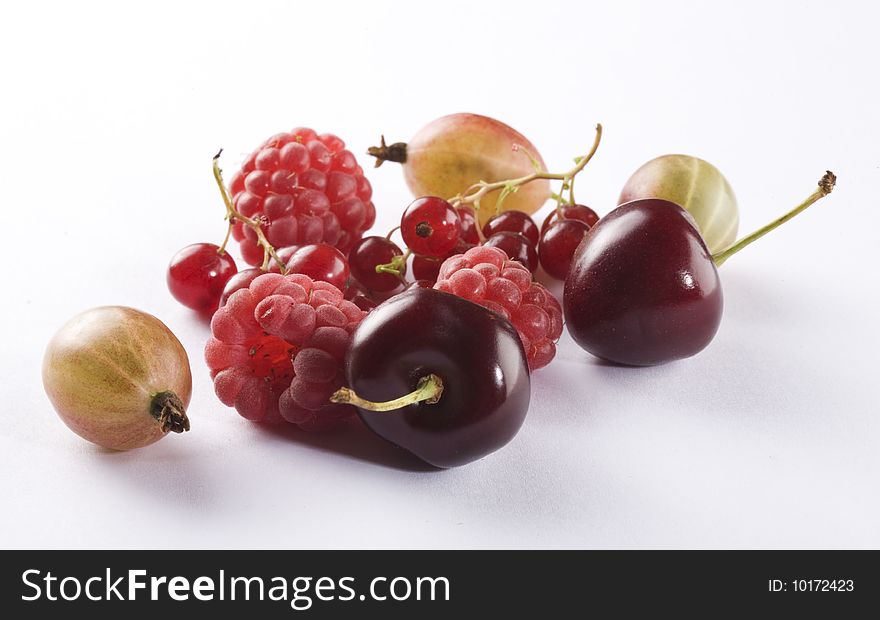 Raspberries, cherrries, red currant and gooseberry on a white background. Raspberries, cherrries, red currant and gooseberry on a white background