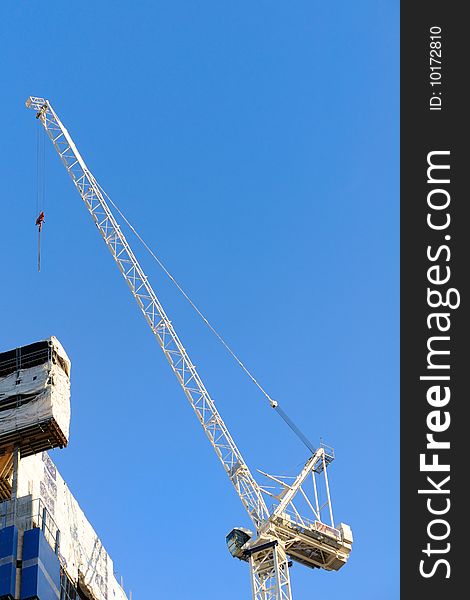 White construction crane with blue sky on background