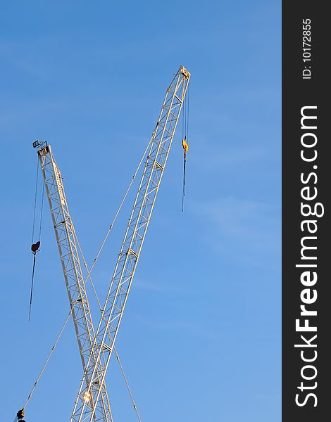 Fragment of a white construction crane with blue sky on background