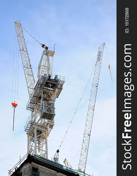 Two white construction cranes with blue sky on background. Two white construction cranes with blue sky on background