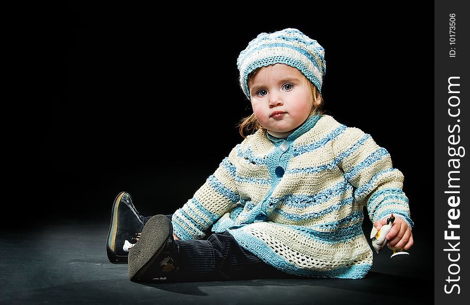 Sitting little baby in a bound suit on black background