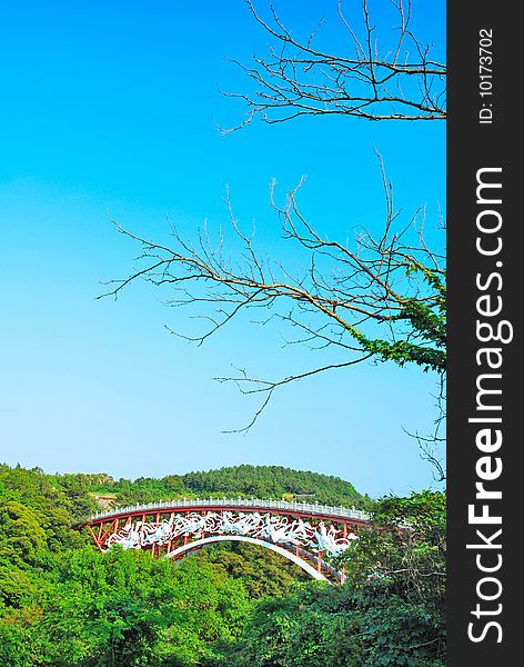 Unique bridge surrounded with nature with barren tree branches in the foreground