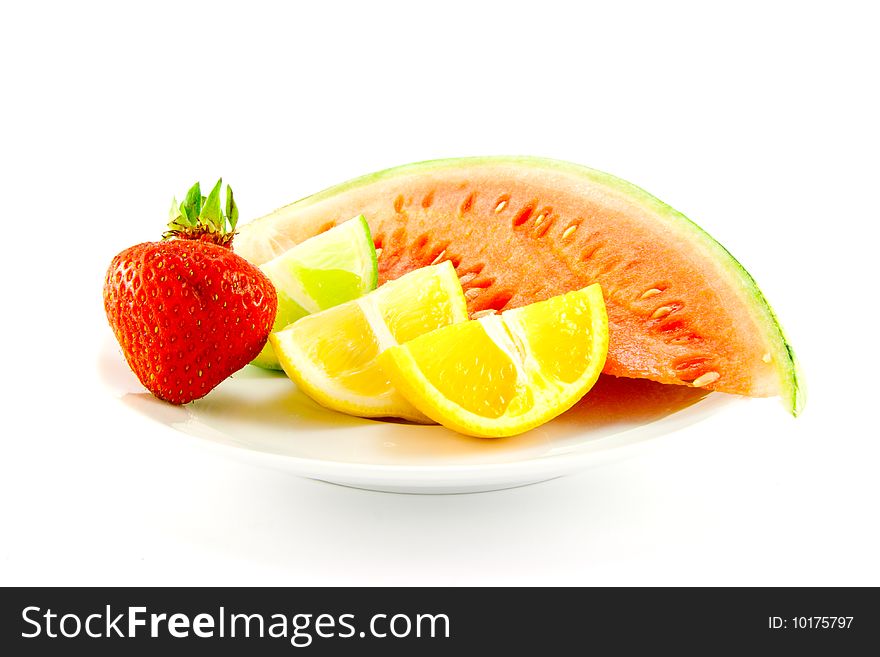 Lemon, lime and orange wedges with a red ripe strawberry and slice of juicy watermelon on a plate with a white background. Lemon, lime and orange wedges with a red ripe strawberry and slice of juicy watermelon on a plate with a white background
