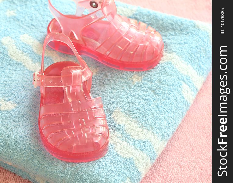 Pink children's footwear on blue and pink towels. Pink children's footwear on blue and pink towels