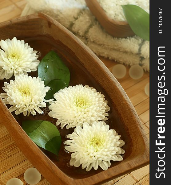 White flowers floating in wooden bowl. spa background