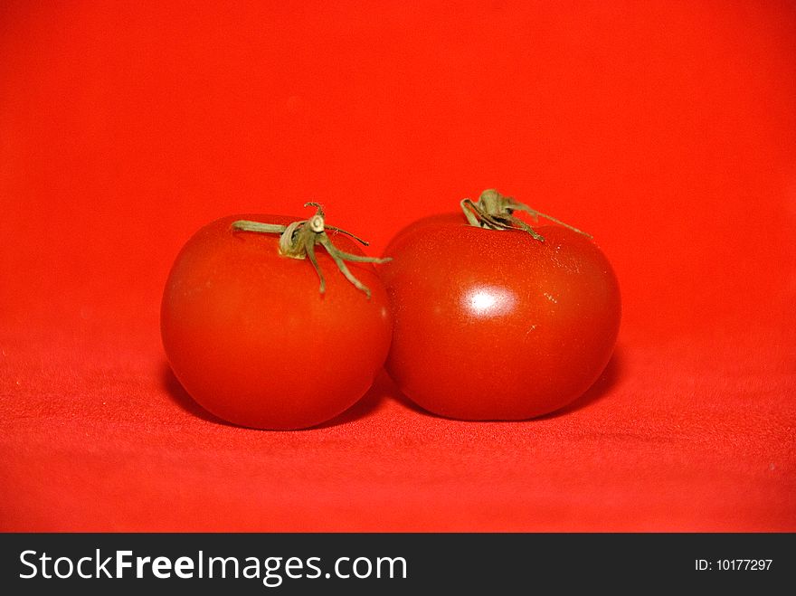 Red tomatos with stalks on red background. Red tomatos with stalks on red background